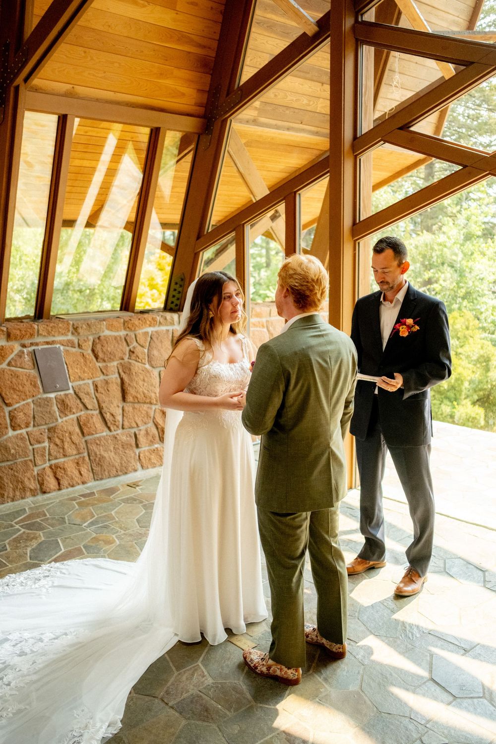 Wedding ceremony in modern chapel with stone walls and wooden beams.