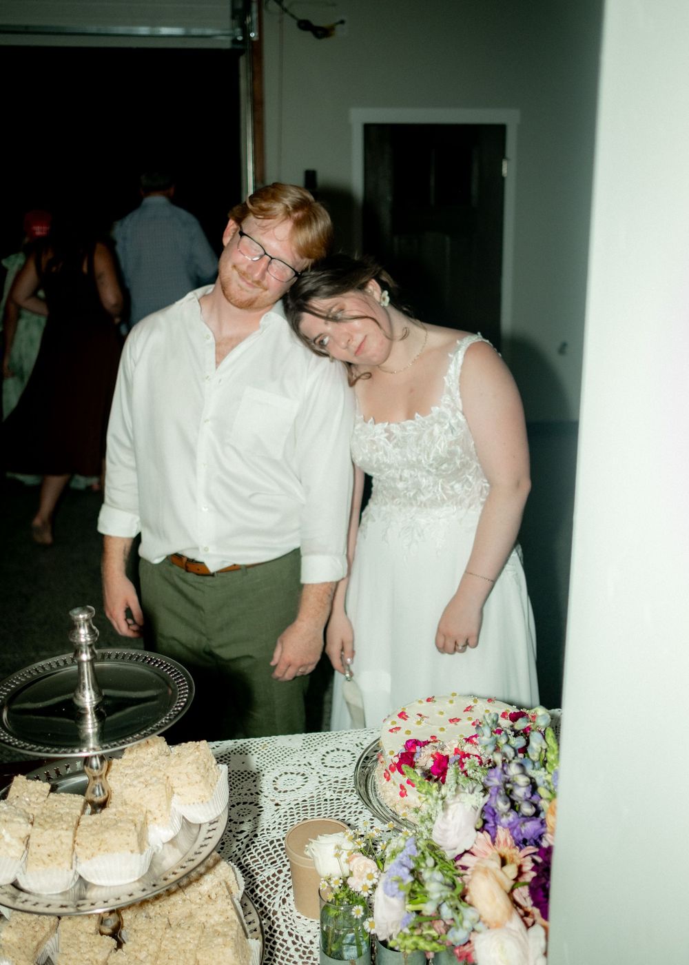 Wedding couple next to tiered dessert display and floral arrangements.