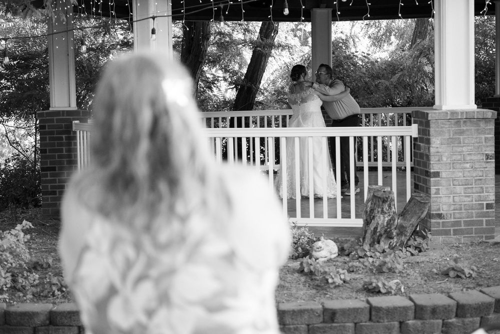 Black and white wedding ceremony photo taken through gazebo railings.