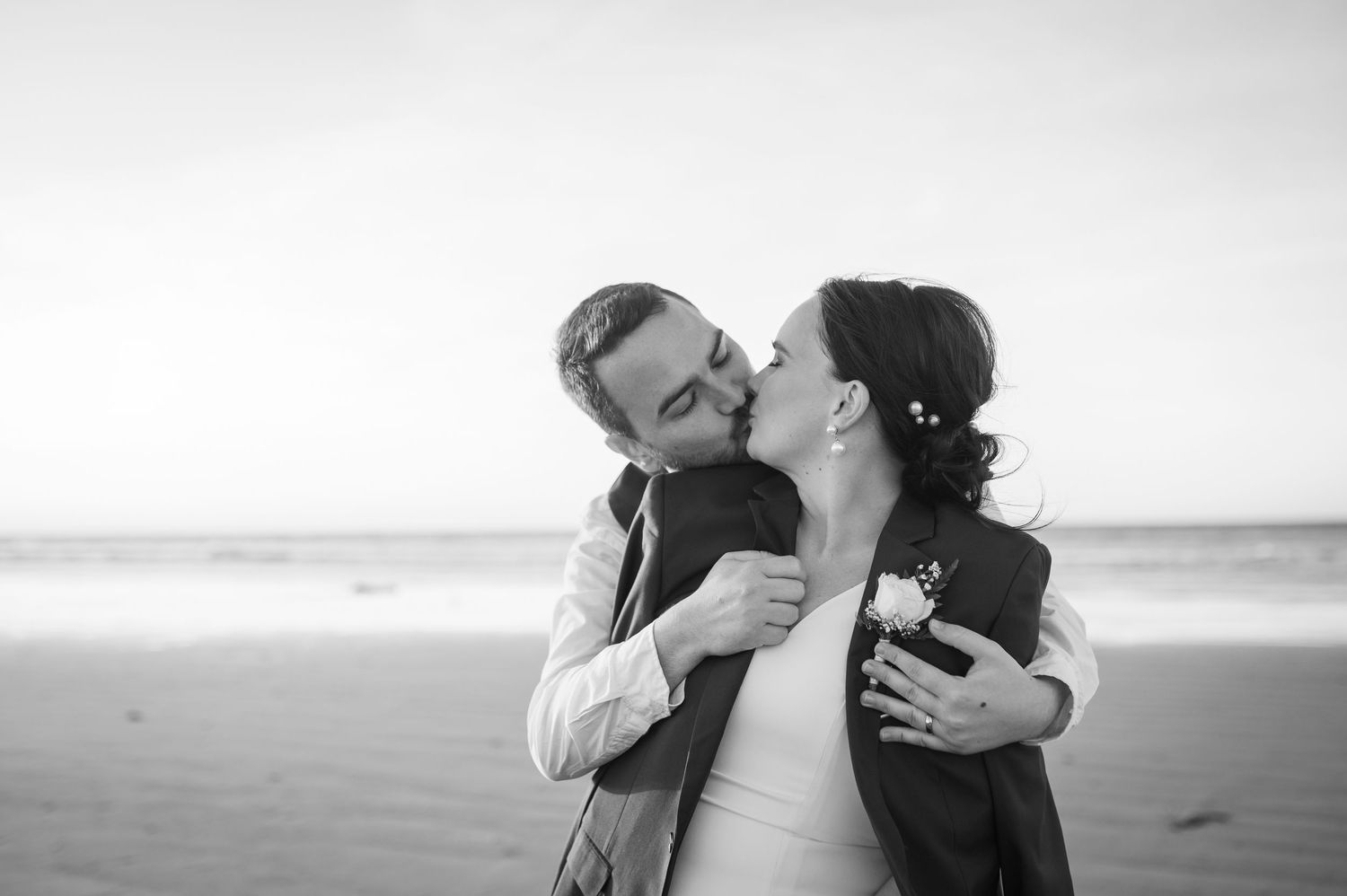 A series of black and white romantic beach photos showing couples sharing tender moments at the seashore.