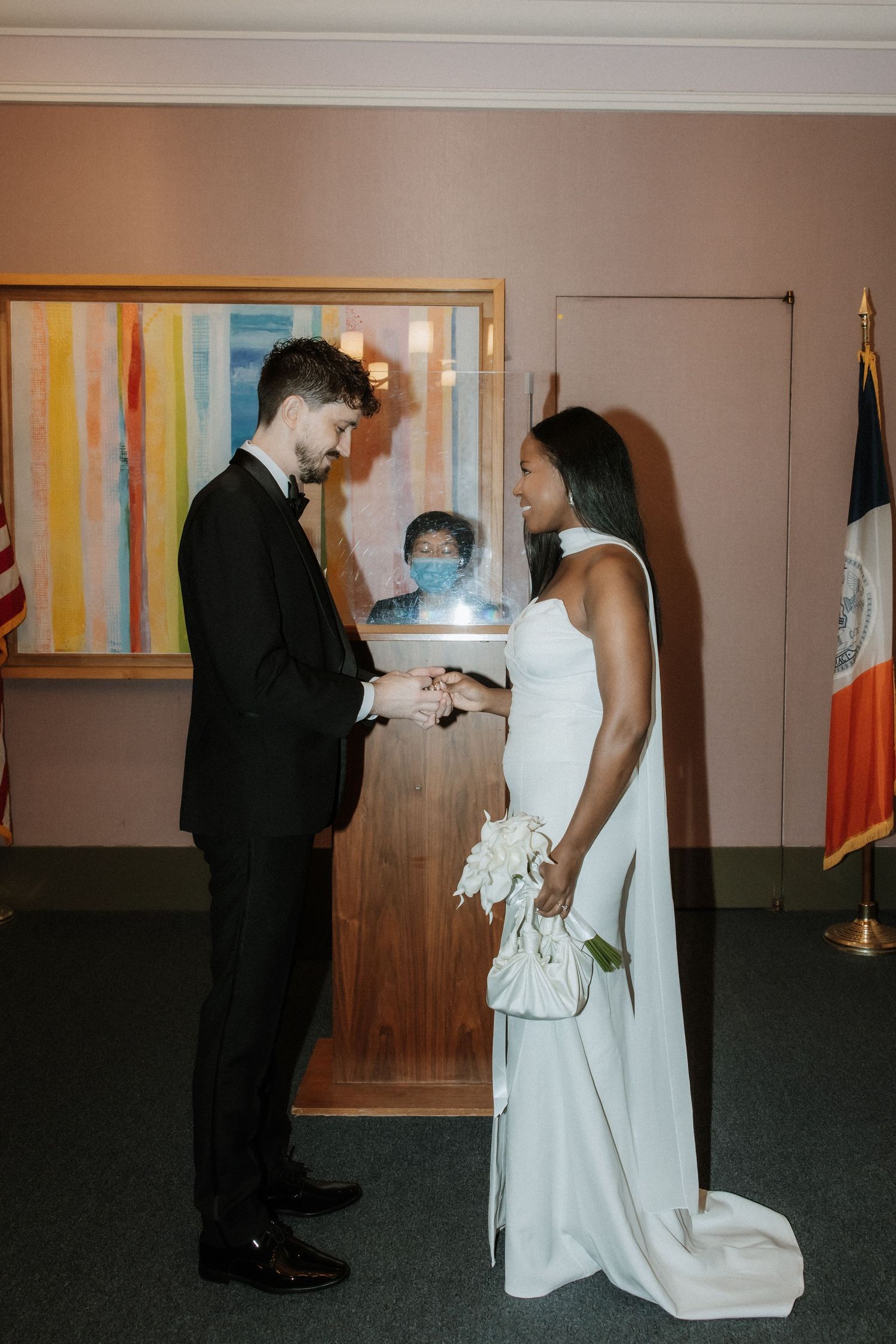 Intimate civil ceremony in front of a colorful abstract painting with flags in the background.