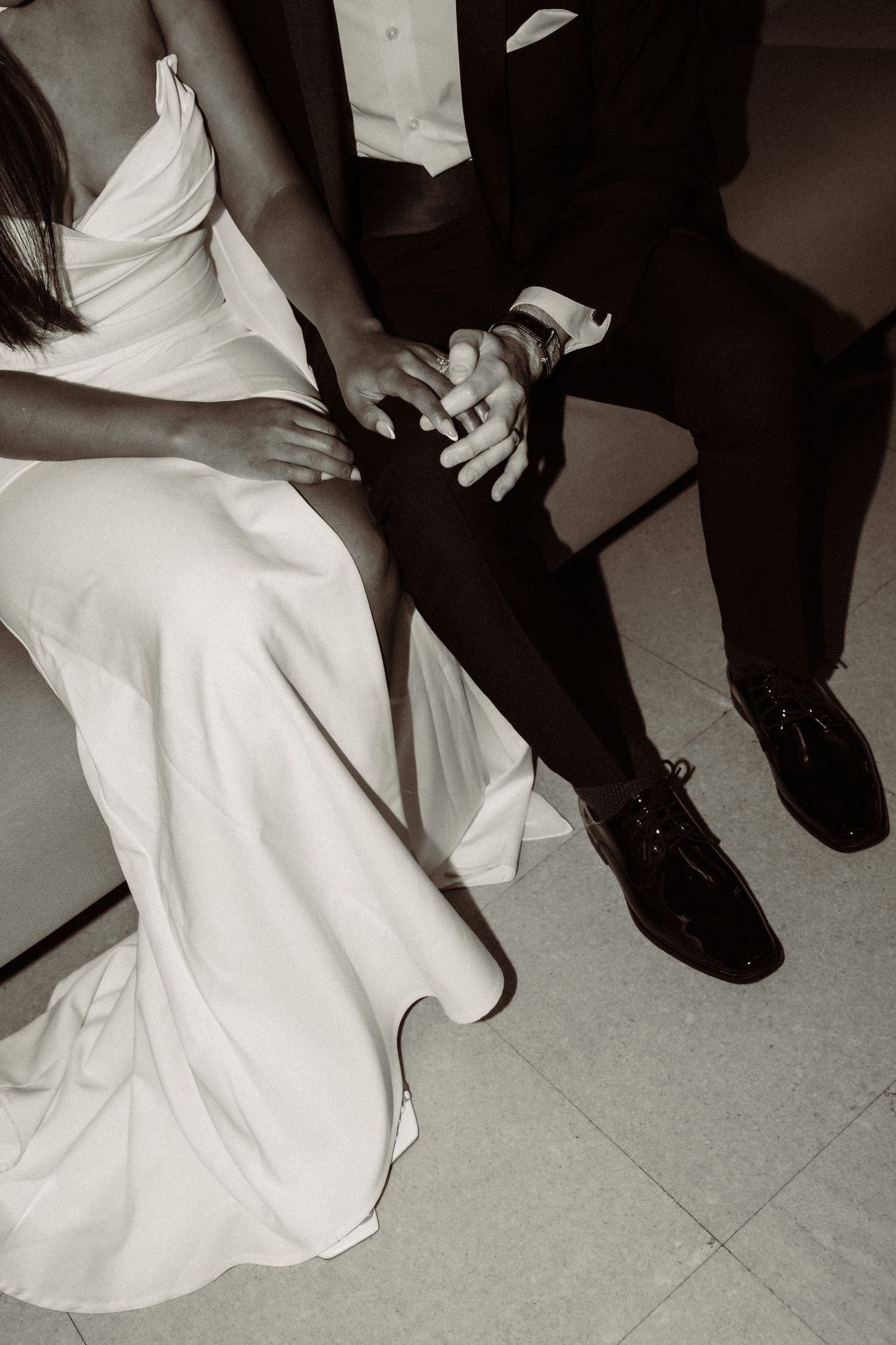 Close-up of formal wedding shoes and white dress hem on a light colored floor.