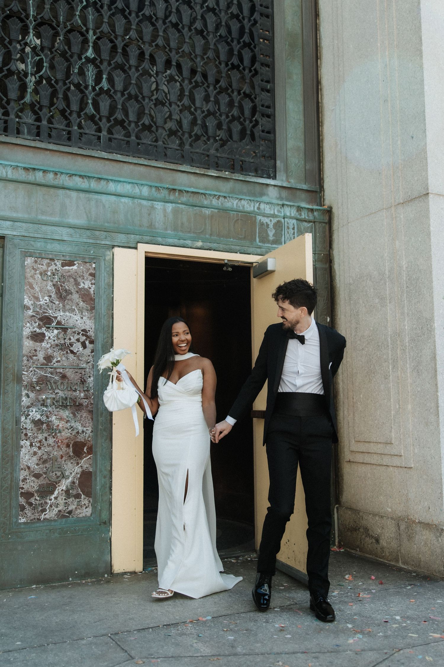 A couple takes wedding photos against a stone wall with decorative iron details.