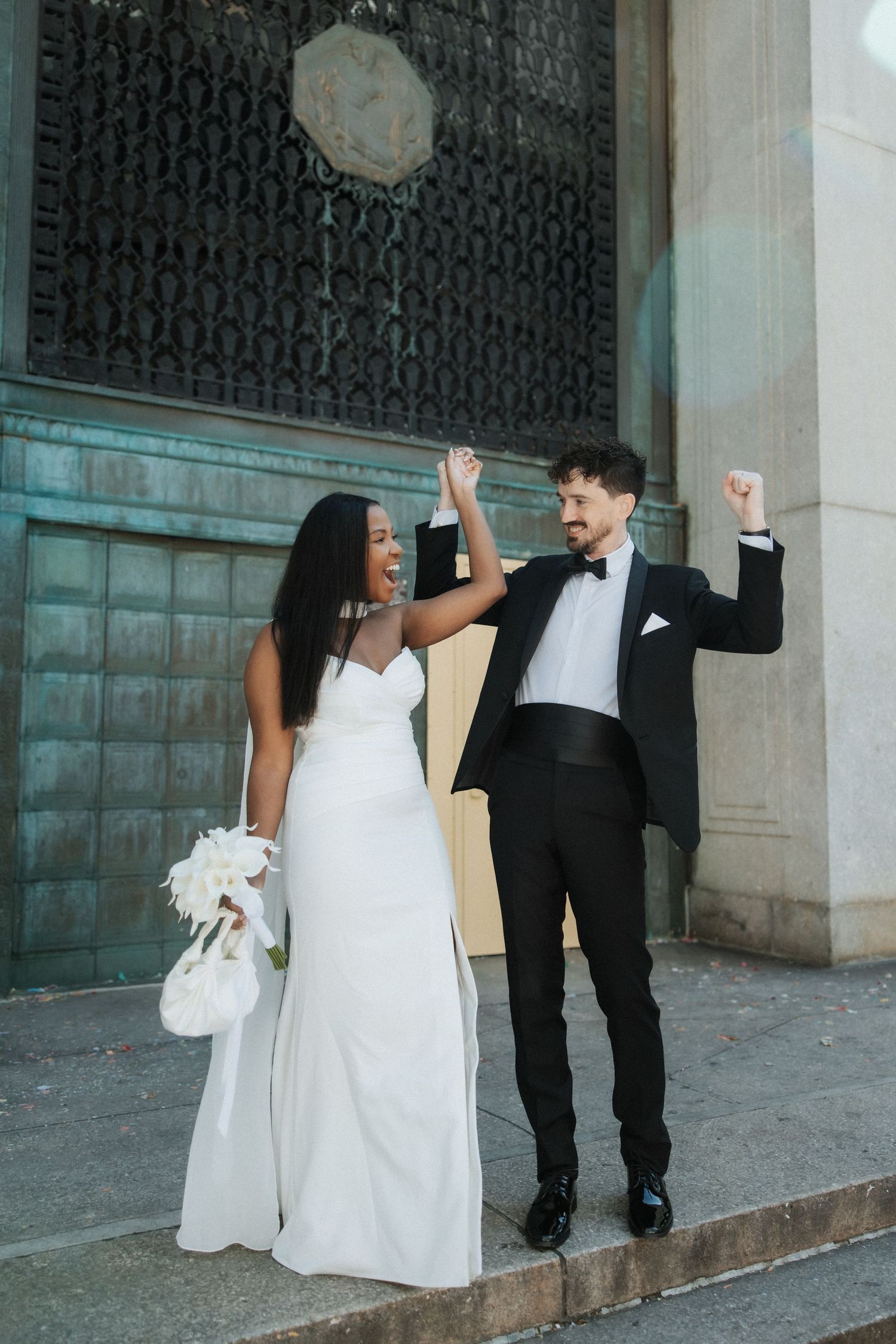 Joyful celebratory moment outside historic building with ornate architectural details.
