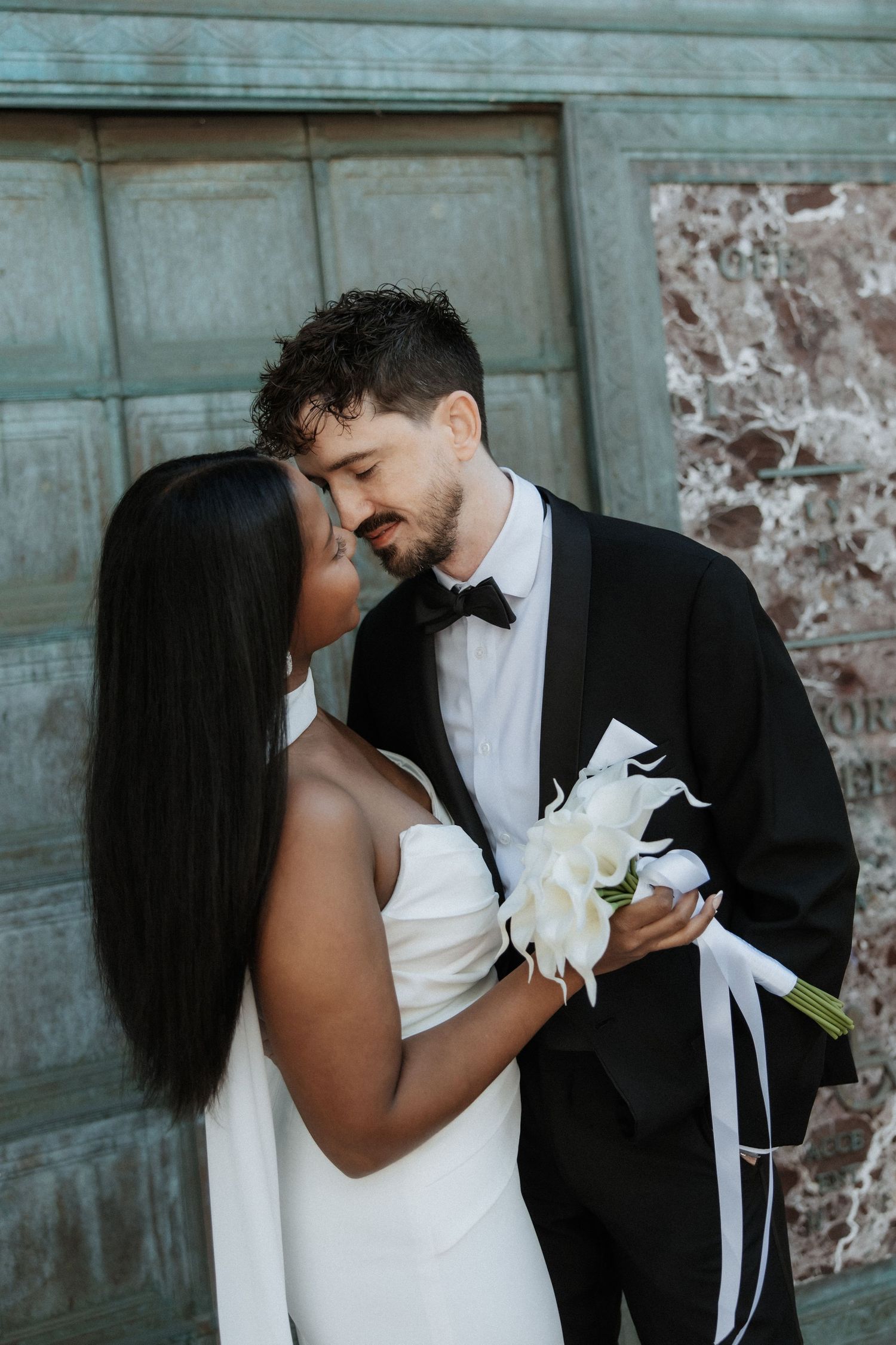 A romantic wedding portrait in front of a vintage blue door with marble accents.