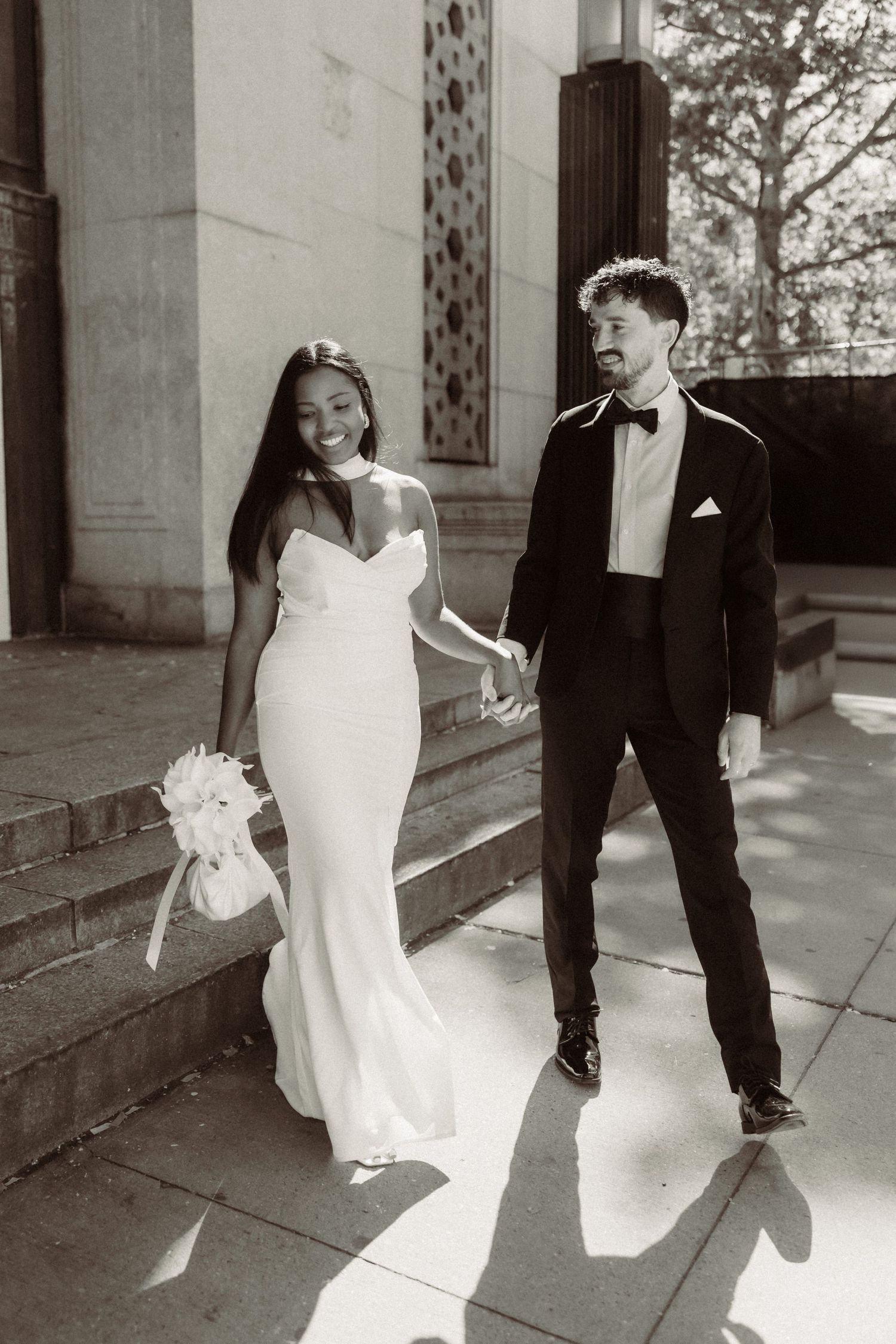 Black and white sequence of a wedding couple walking together on stone steps near columns.