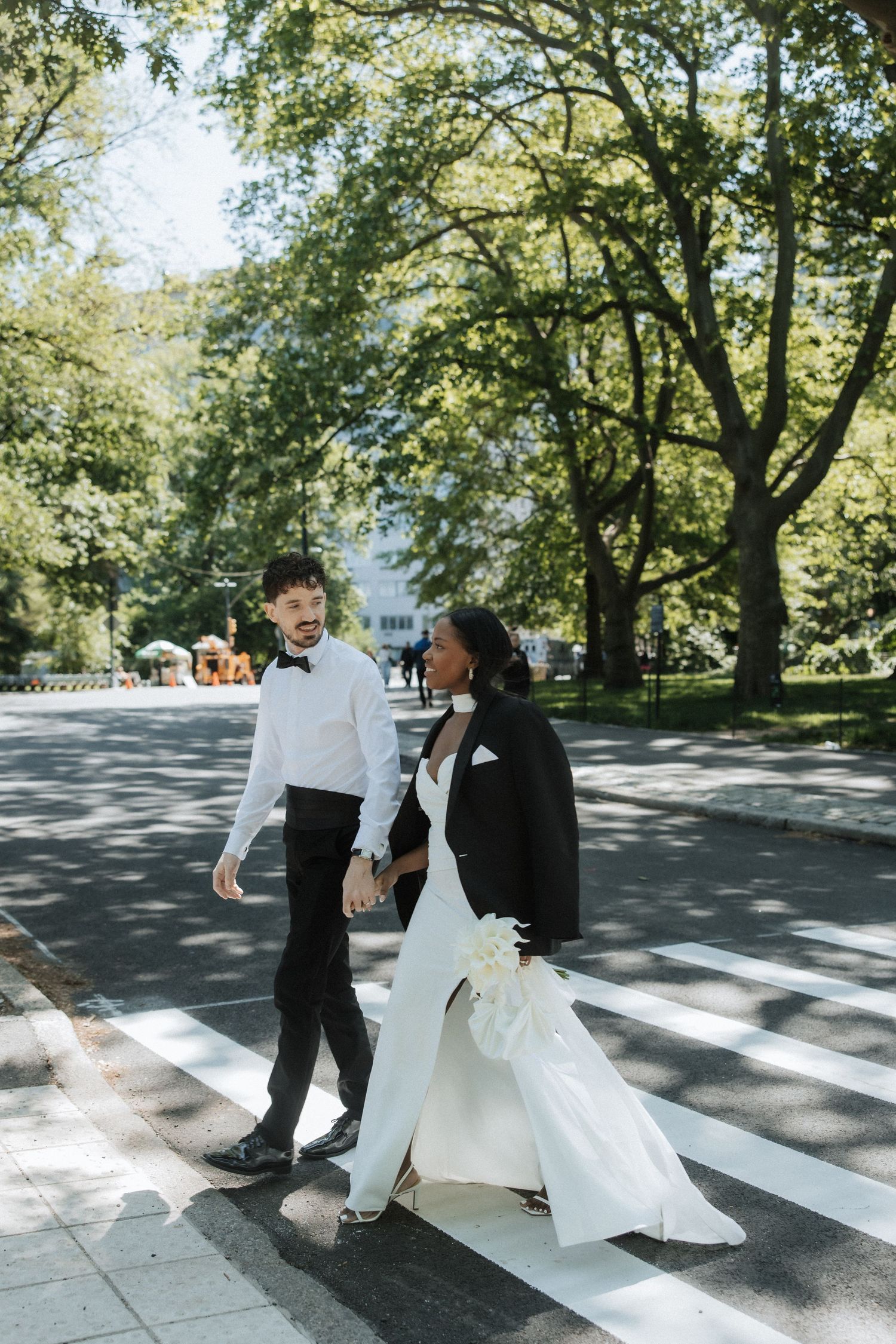 Couple dances playfully on a tree-lined street during their wedding photoshoot.