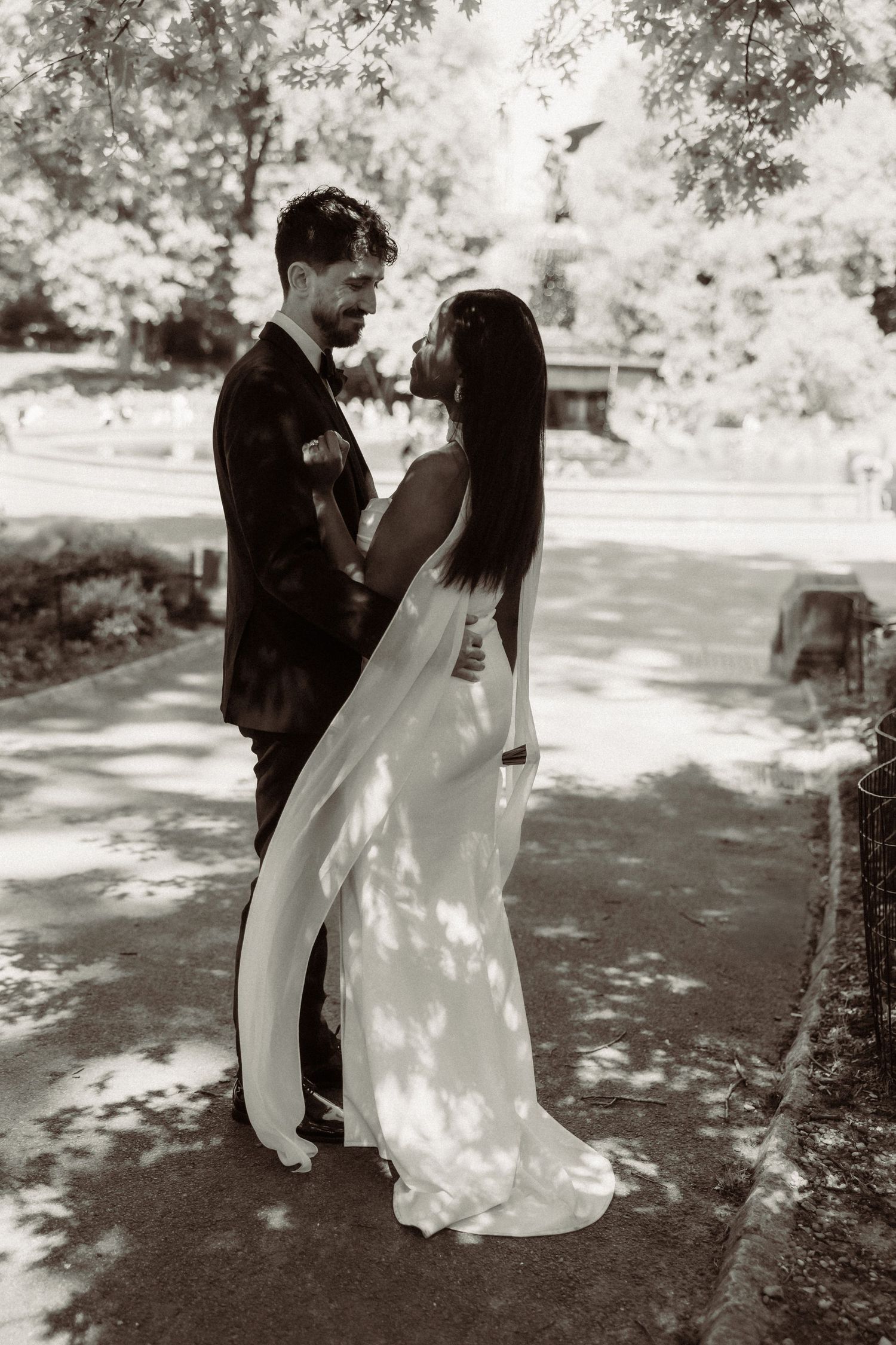 A romantic wedding photoshoot in a sunlit garden with dappled light filtering through trees.