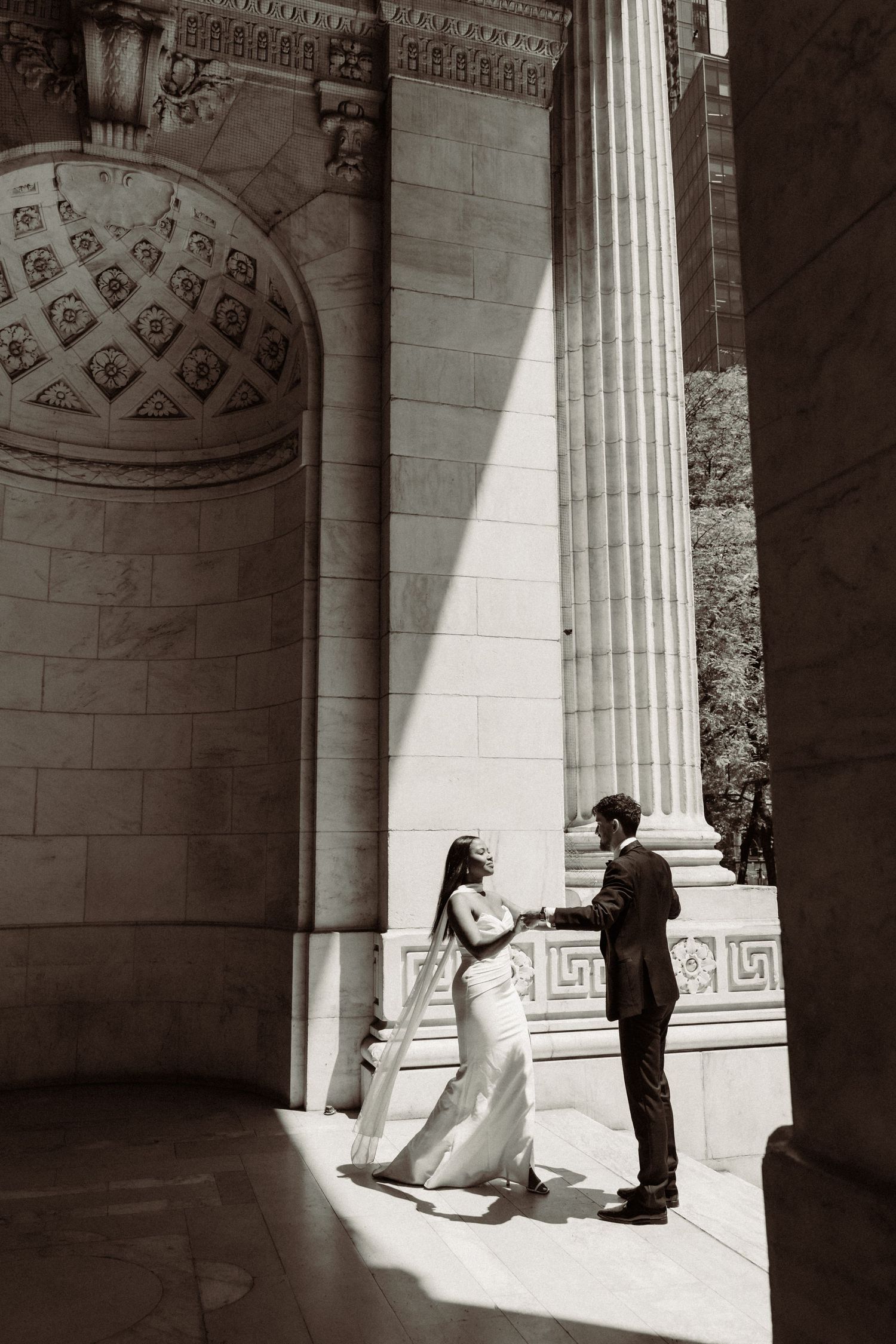 Dramatic black and white wedding portraits captured between grand architectural columns.