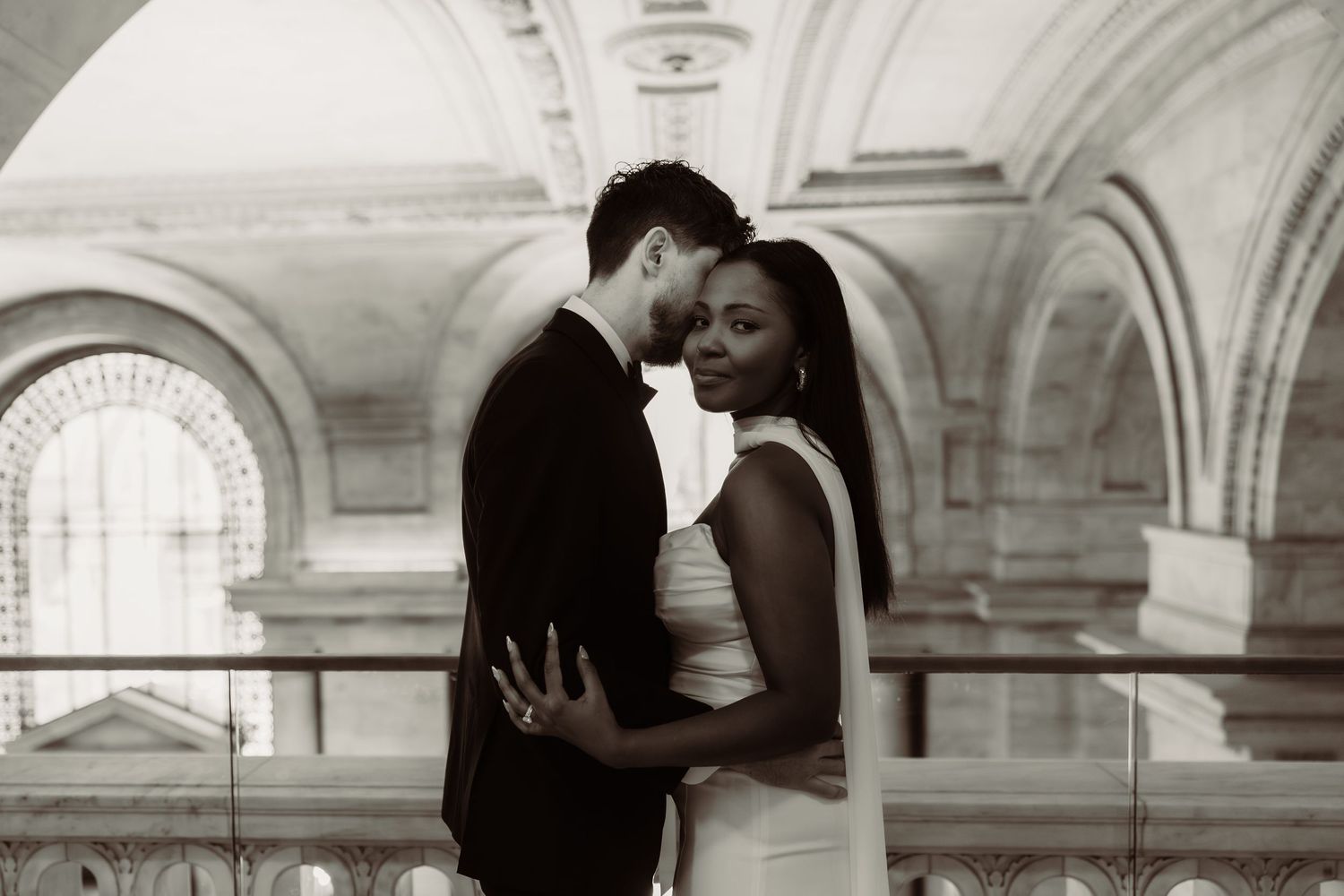 Black and white wedding sequence captured under ornate stone archways.