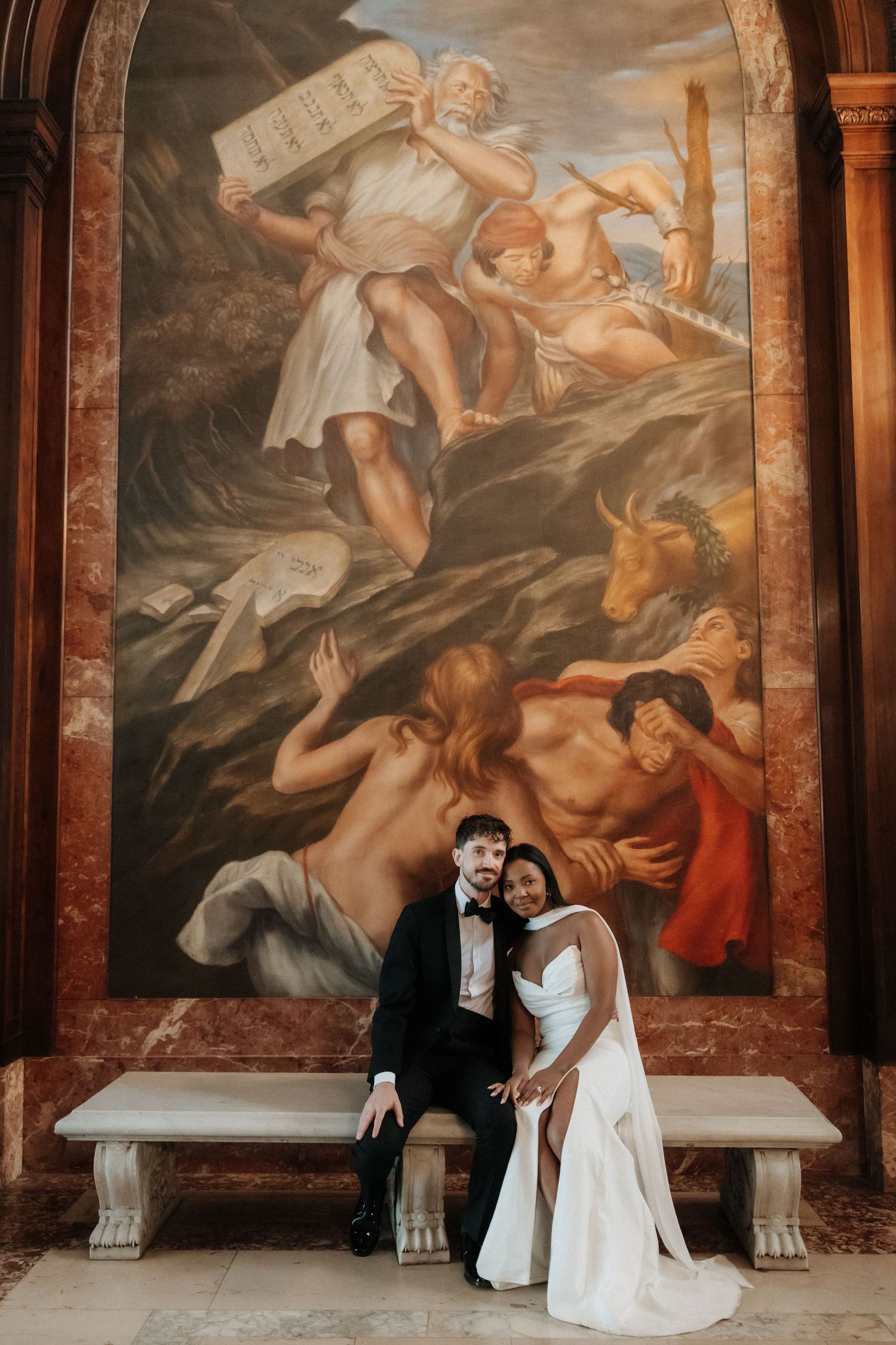 Wedding portraits taken against dramatic Renaissance-style wall murals and marble columns.