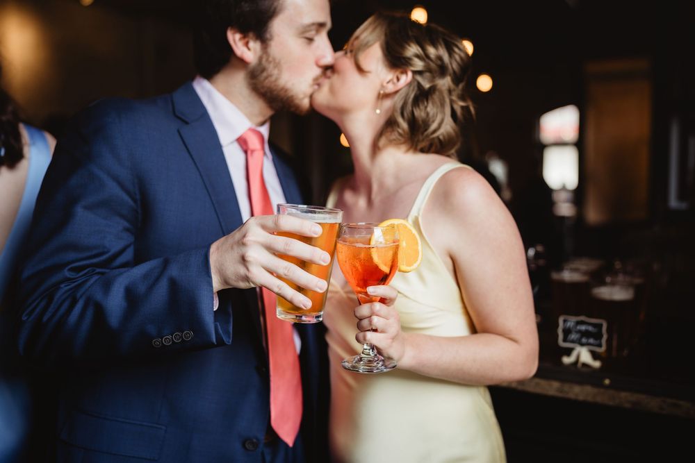 A couple in formal attire sharing colorful cocktails at an elegant bar reception.