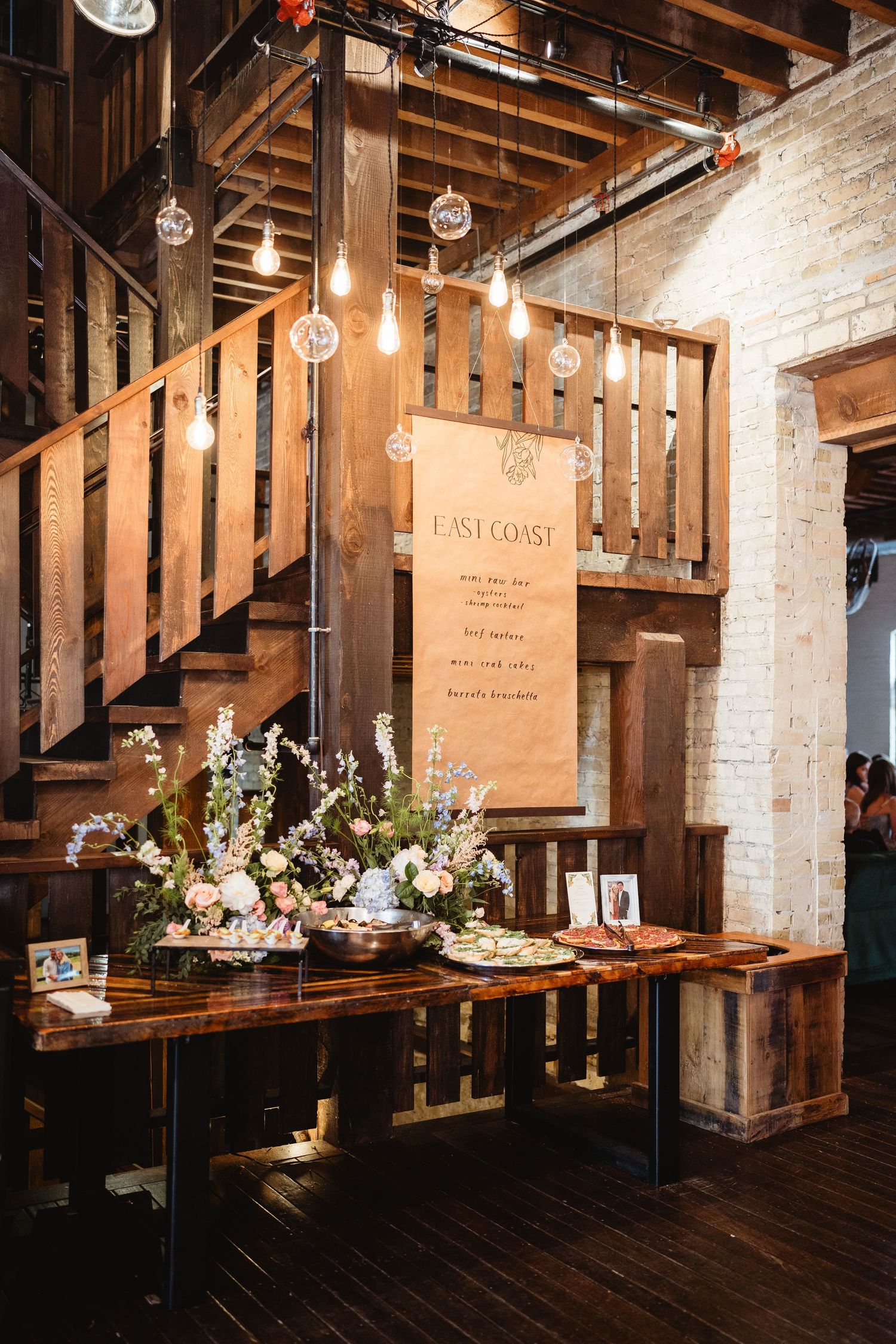 Rustic wedding venue featuring wooden beams, hanging lights, and elegant table settings.
