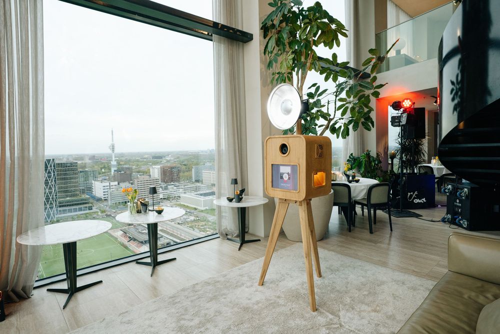 Stylish wooden photo booth standing in luxury penthouse venue with floor-to-ceiling city views.
