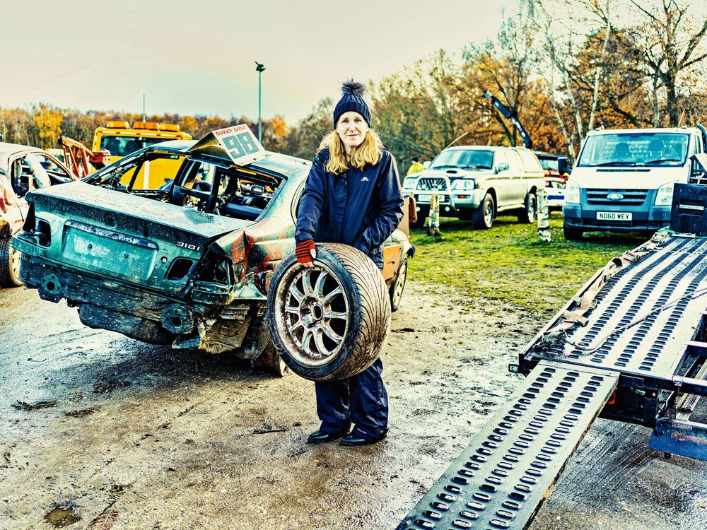 Banger racers, a woman holds a car tyre - damaged from a race at Ipswich track, photographed by John Ferguson