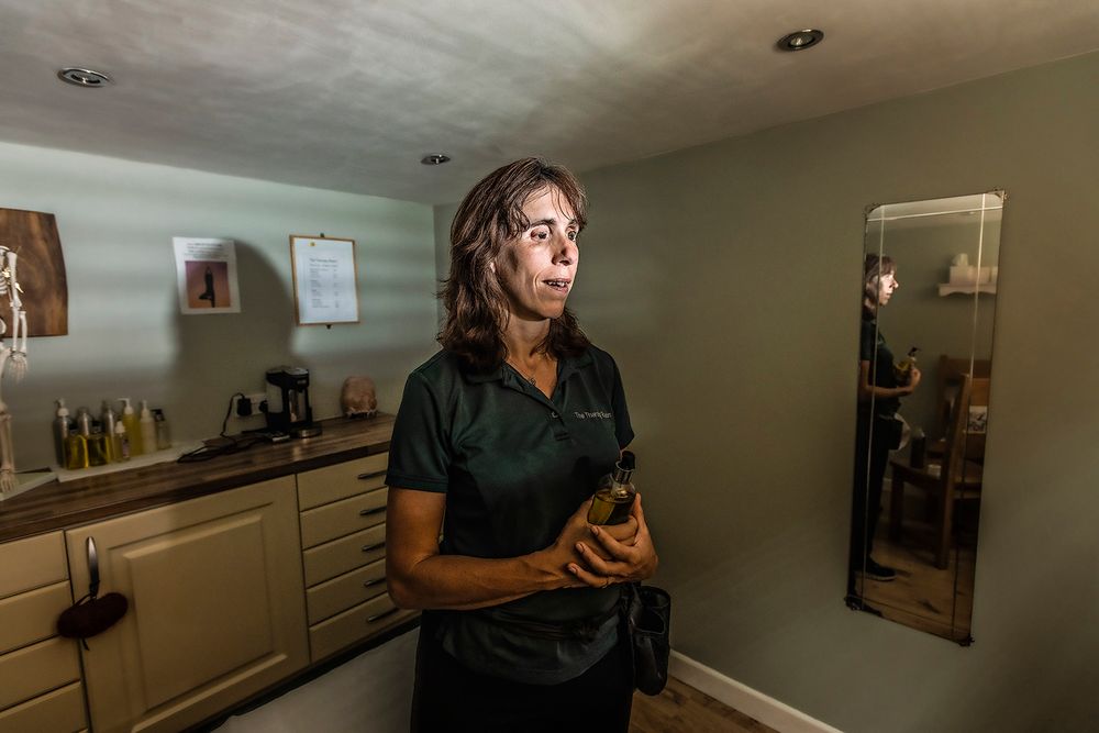 Documentary portrait of Messasuer Rebeeca Lake standing in her softly lit treatment room, Ipswich, Suffolk.