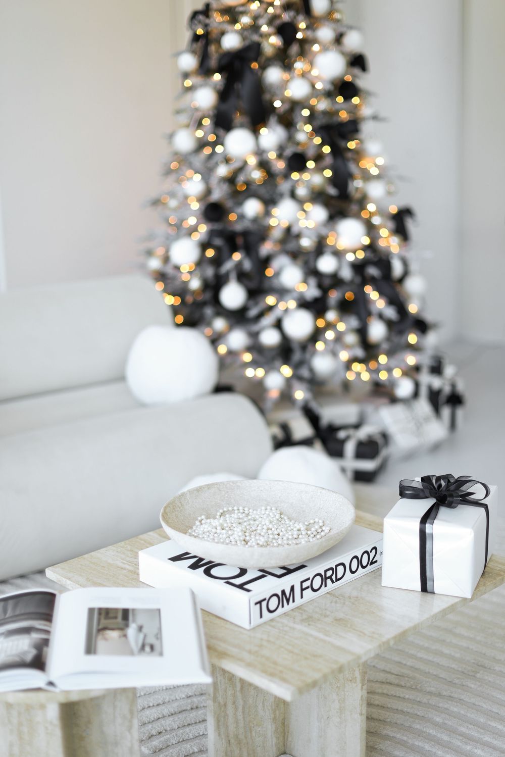 Modern minimalist coffee table styling with fashion books and Christmas tree decor in monochromatic white tones.