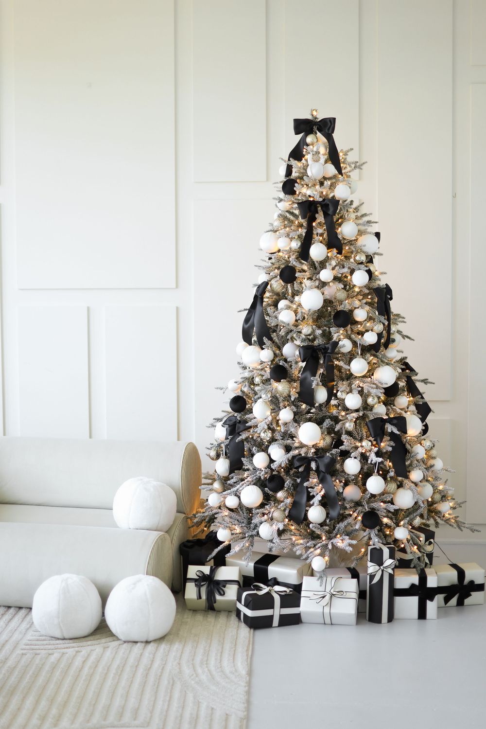 A chic black Christmas tree adorned with white ornaments and matching black and white presents underneath.