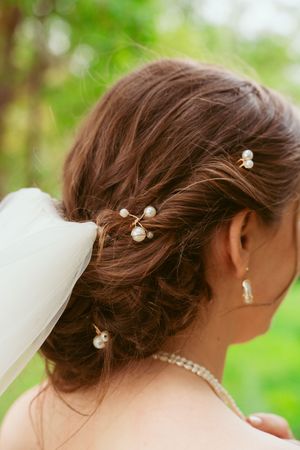 Elegant bridal hairstyle with pearl flower pins and veil detail captured in natural outdoor lighting.