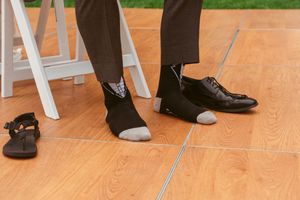 Dress shoes and socks shown on tiled floor next to small child's shoe.