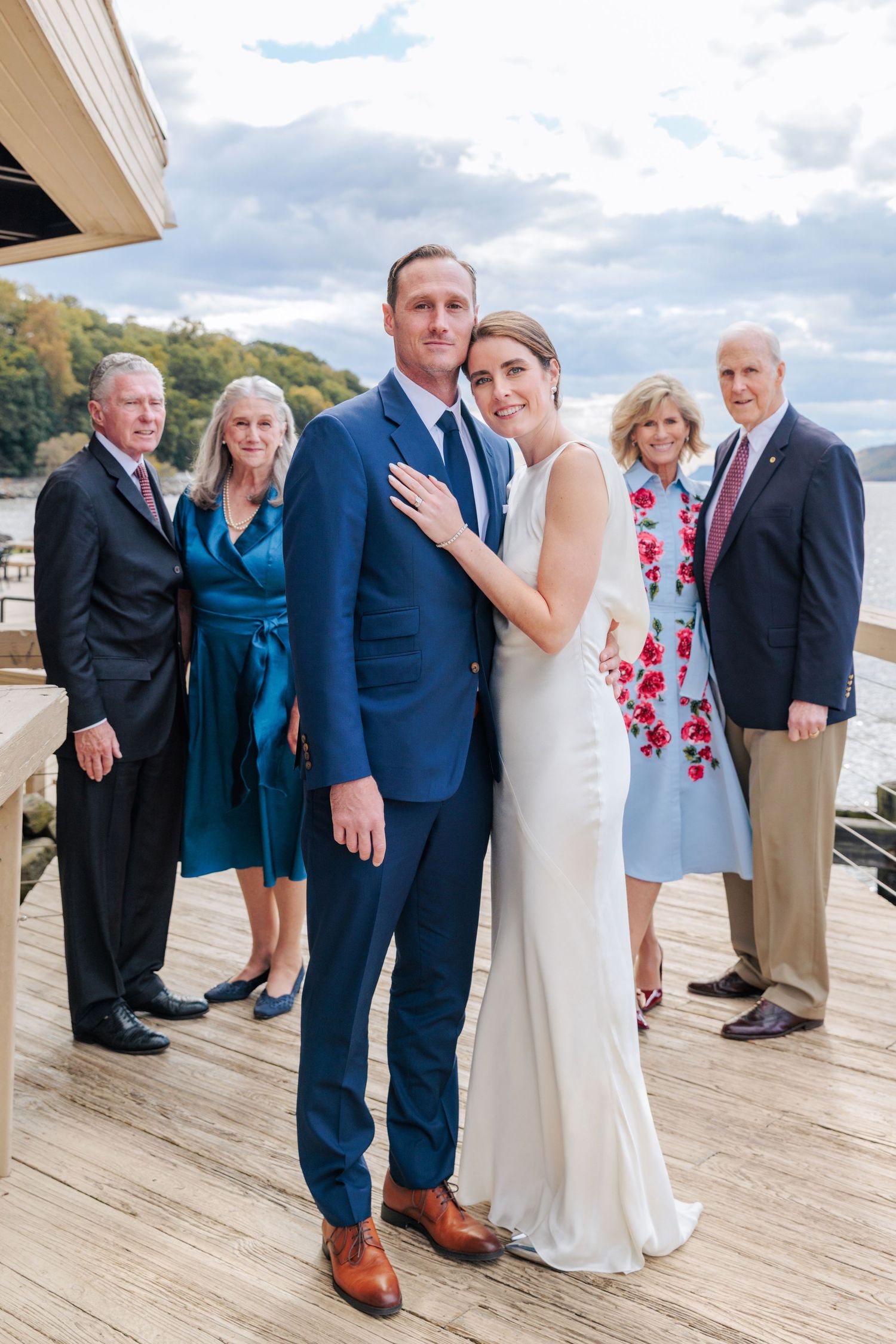 Bride and Groom stand close together with both of their parents set back behind them.