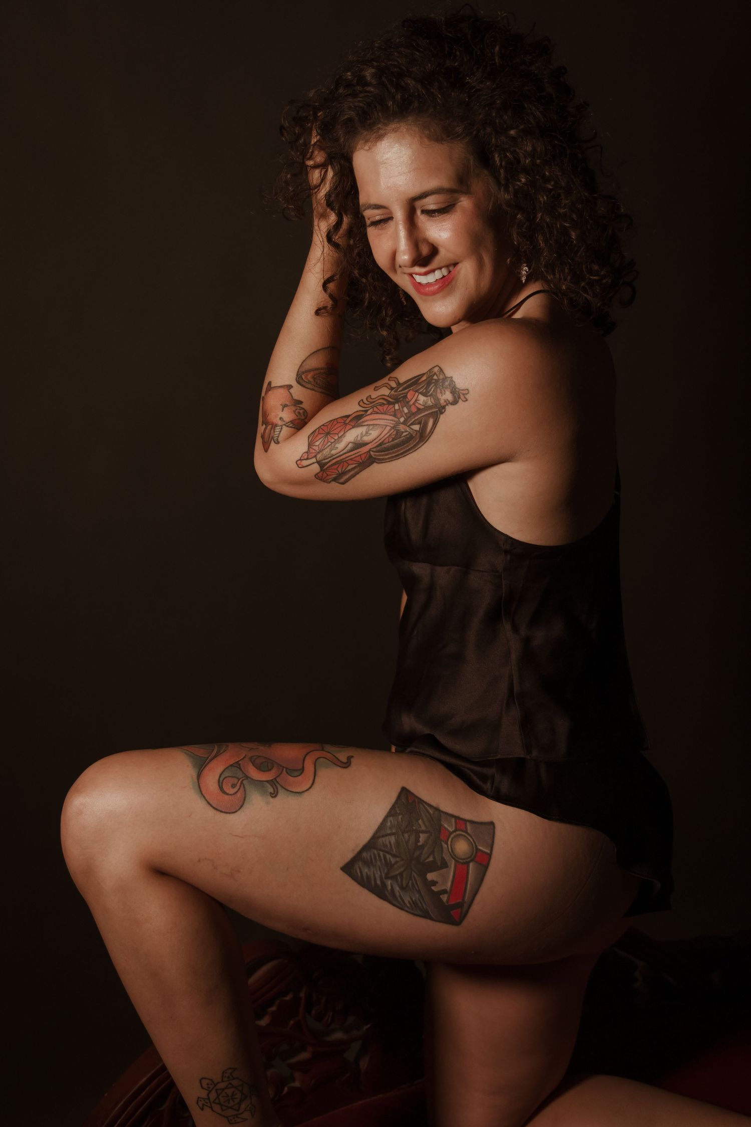 Intimate boudoir photo showcasing tattoo art in dramatic lighting.