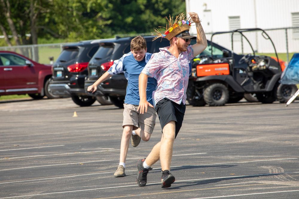 Two players high five and celebrate in a parking lot with cars and utility vehicles in the background.