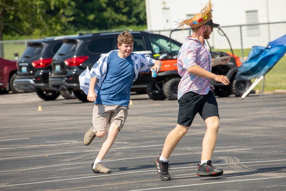 A sequence of people practicing martial arts kicks in a parking lot during training exercises.