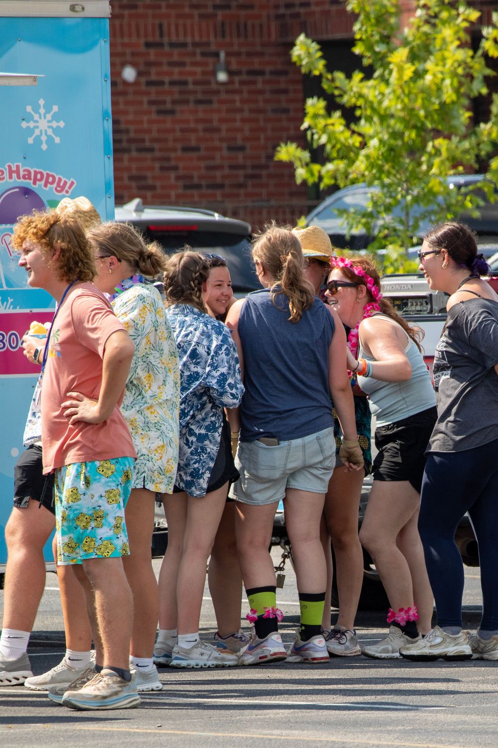 A group of dancers perform a synchronized dance routine in a line formation outside a brick building.