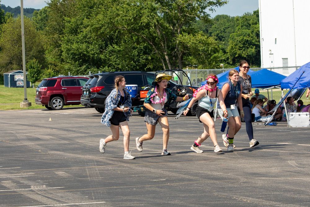 Athletic participants sprint off the starting line during an outdoor race in a parking lot.