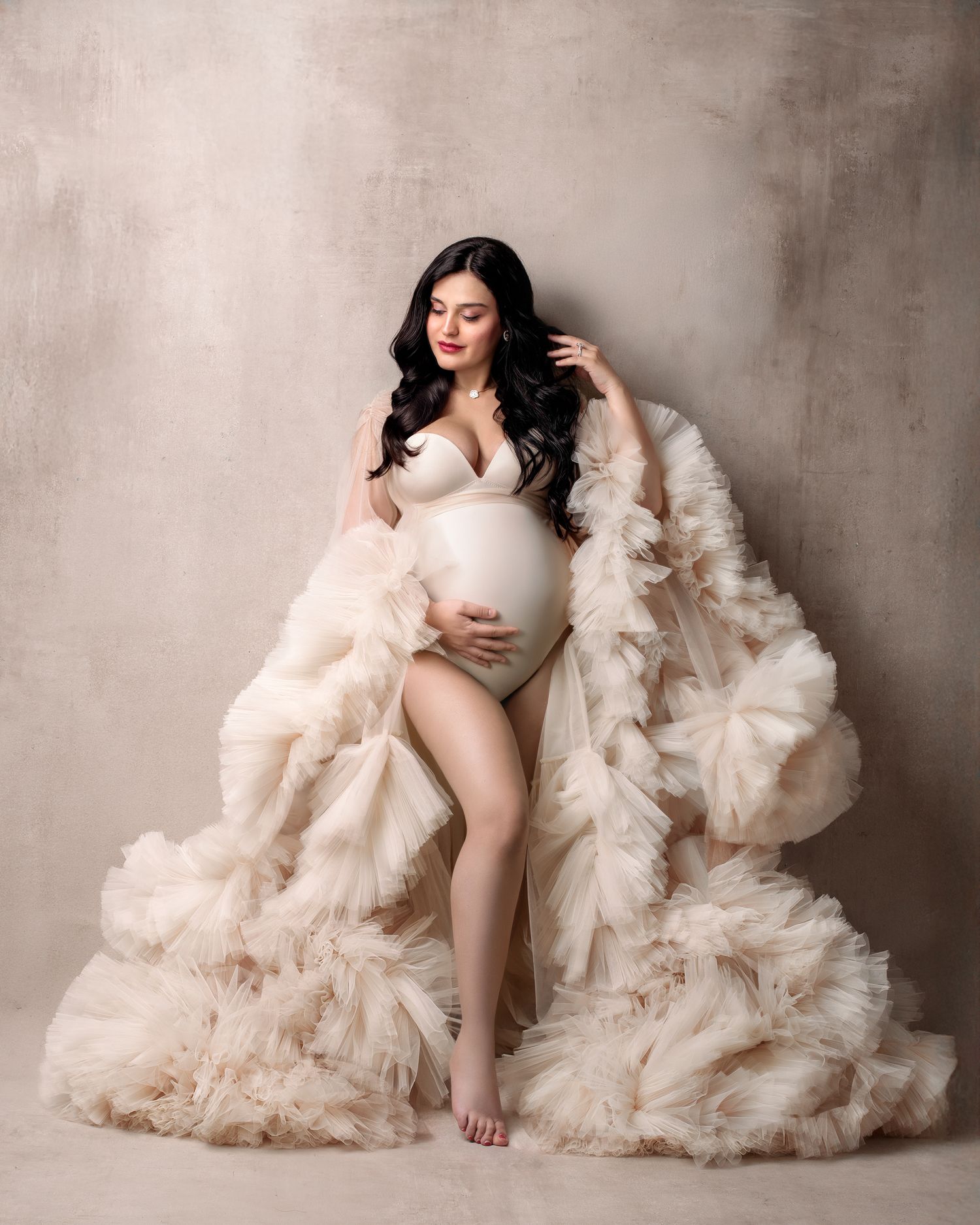 Luxury studio maternity session Sydney: mum in a stunning couture robe and bodysuit against hand painted canvas backdrop.
