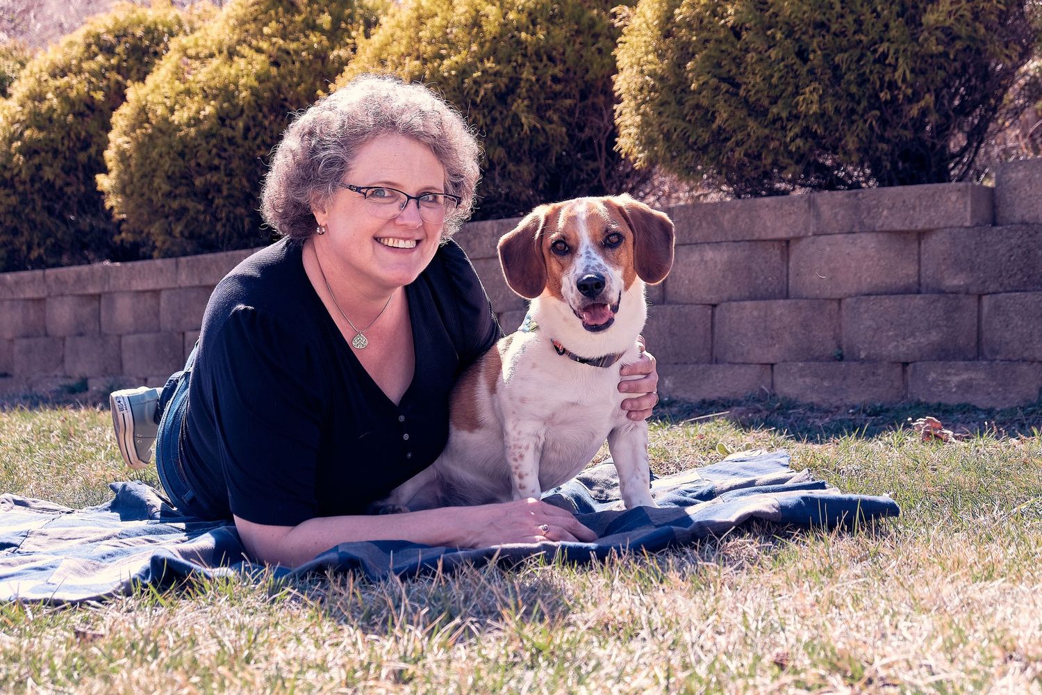 A person in black clothing lies on the grass with a Jack Russell terrier dog in multiple similar poses.