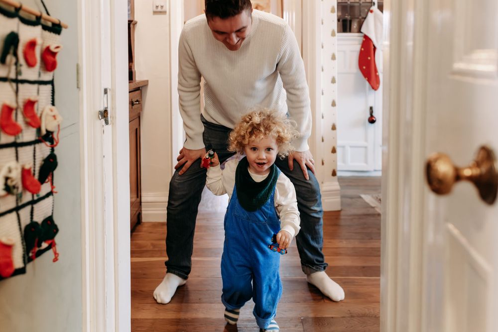 A group of people enjoying playful moments together in a bright interior hallway with white walls.