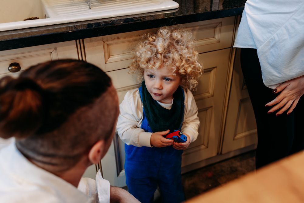 A child and adult work together in a kitchen preparing food on a wooden cutting board.