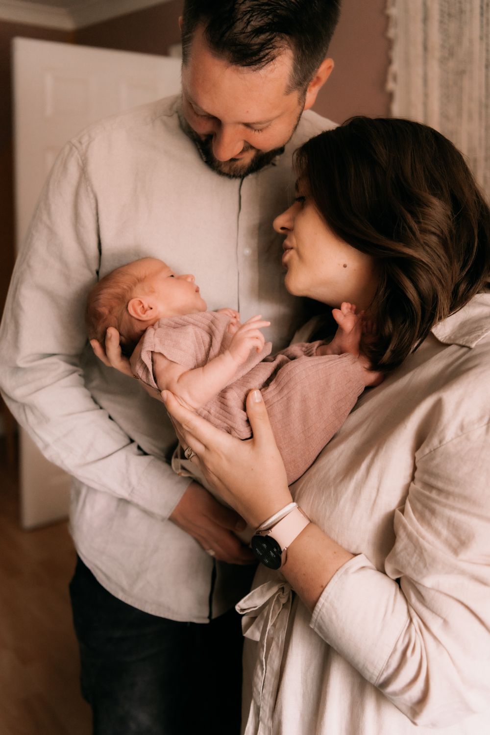 A tender family moment as new parents cradle their newborn baby while sharing a warm, intimate moment together at home.