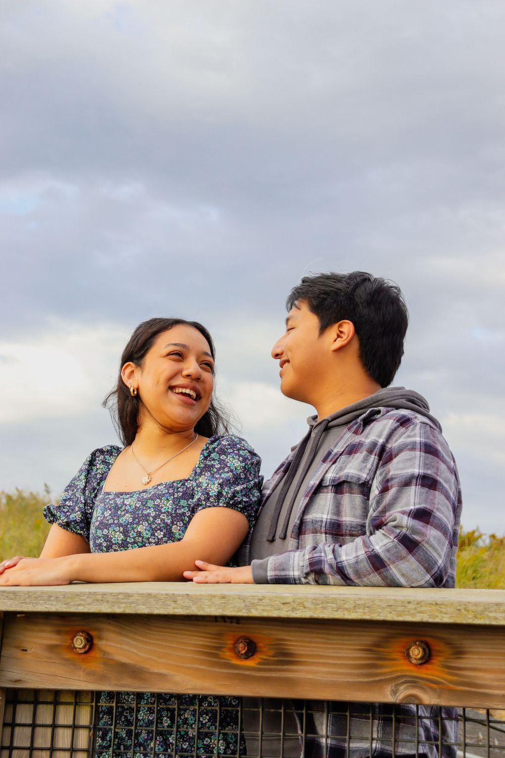 A couple shares a joyful moment together on a wooden observation deck.
