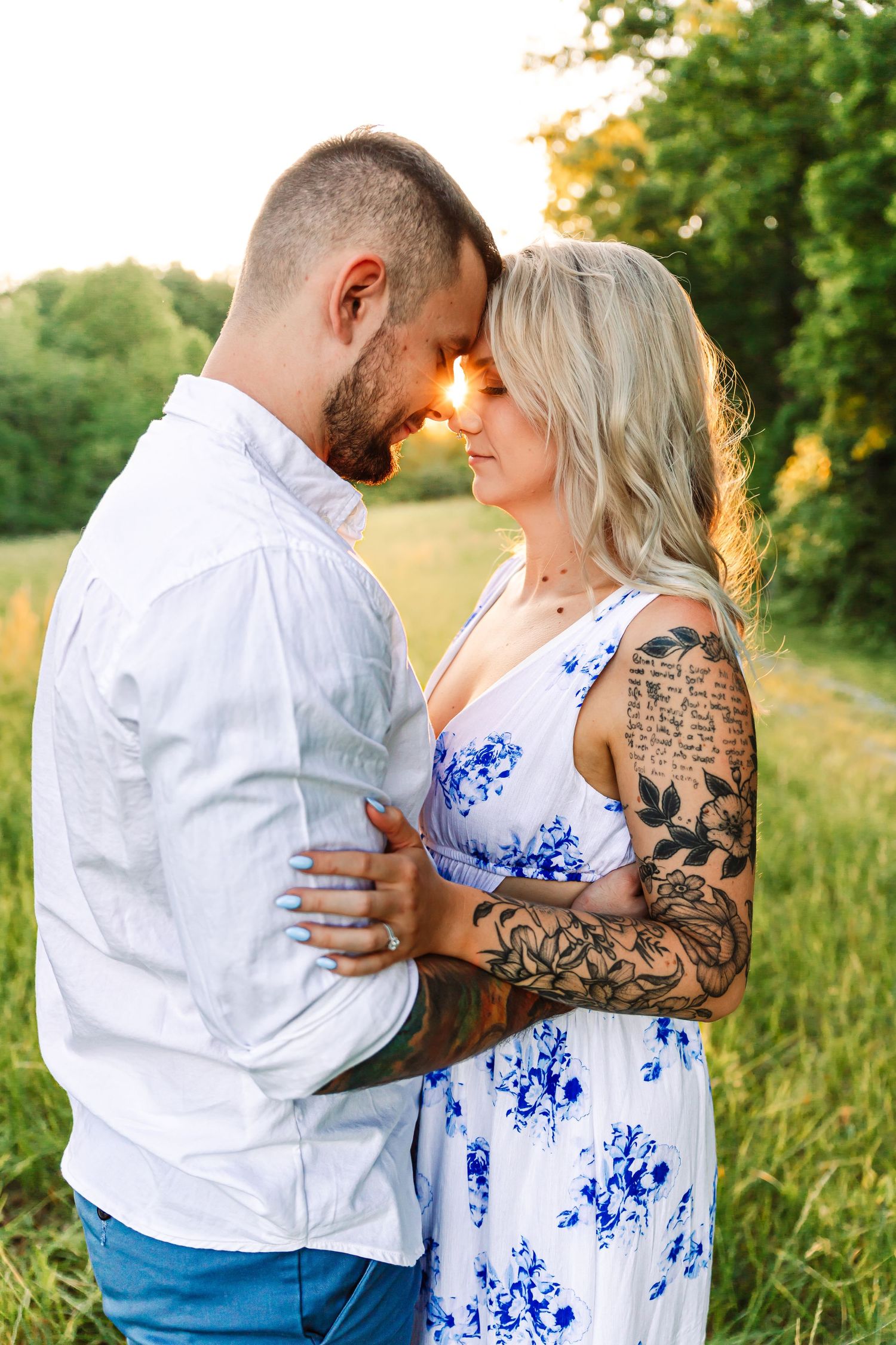 Intimate engagement photos in a sunlit meadow showing couple in white and blue floral dress.