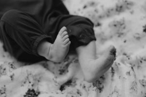 Black and white close-up of tiny feet resting on a floral patterned surface.