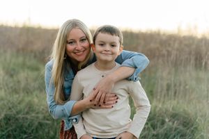 Parent and child share warm embrace outdoors during sunset photo session.