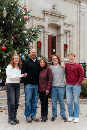 Holiday family portrait in front of Sheriff's office with decorated Christmas tree.