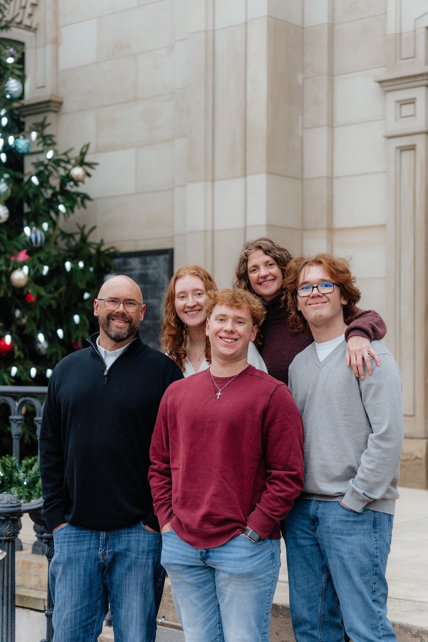 Winter portrait of group standing by decorated Christmas tree outside historic building.