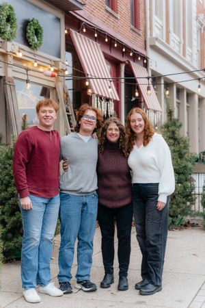 Group photo outside brick storefront with striped awning and holiday decorations.