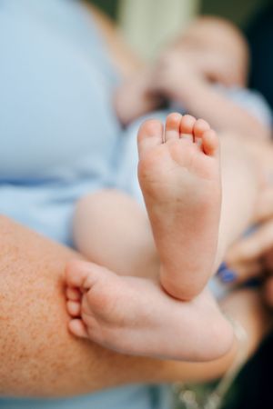 Close-up of tiny baby feet resting on adult hands.