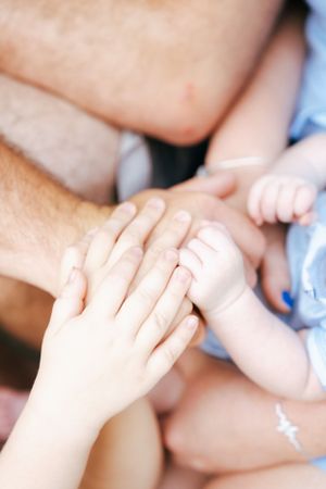 Close-up of hands touching in tender family moment.