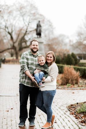 Happy family posing together on brick walkway with statue in background.