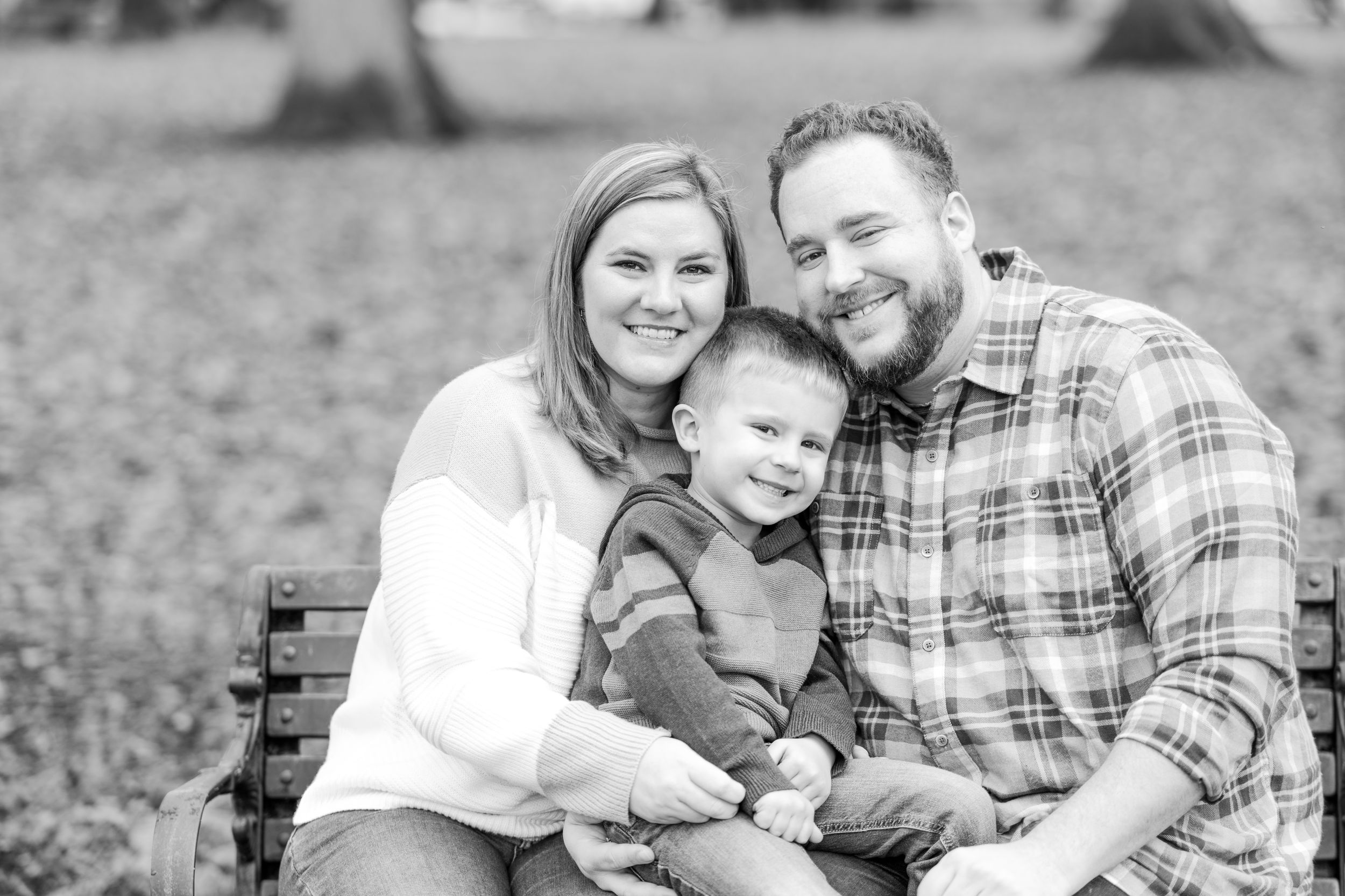 Family sitting together on park bench during fall season.