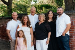 Extended family members pose together for a portrait in coordinated white and black outfits.