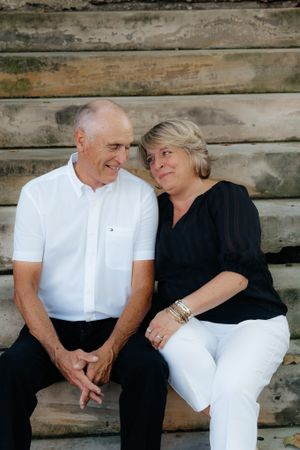 A couple shares an intimate moment while sitting on wooden steps.