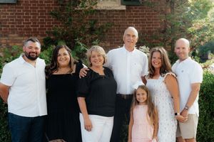 Extended family members pose together in coordinated outfits against a brick building.