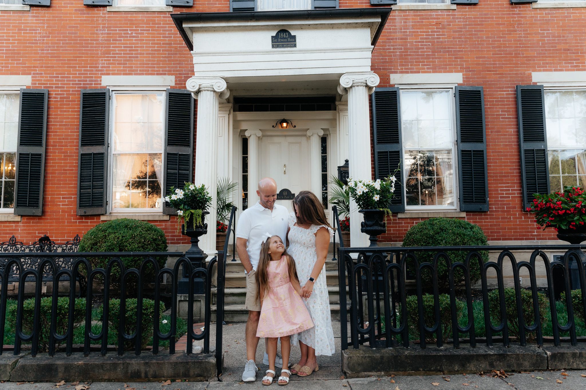A family stands together on steps of a historic brick building.